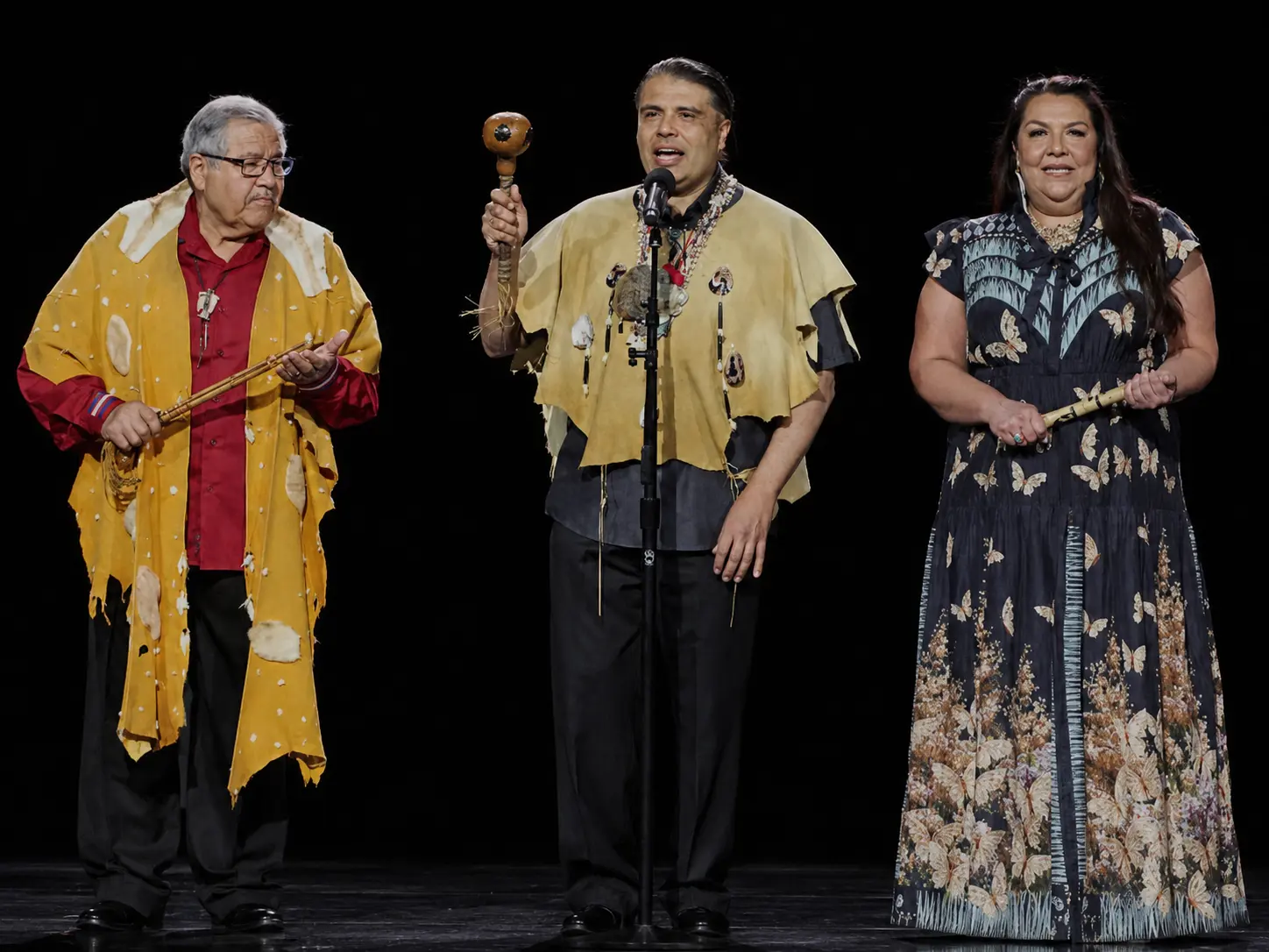 Three ensemble members performing on stage